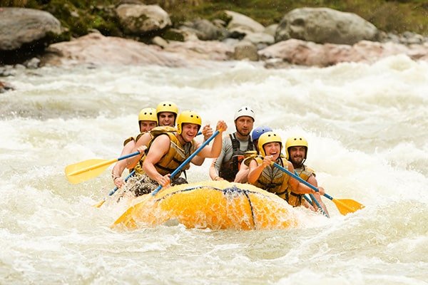 Close-up of rafters paddling through splashing waves
